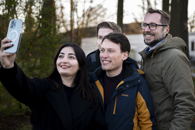 Ein junger Mann macht mit 2 anderen ein Selfie