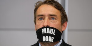 Der Rechtsextremist Sven Liebich mit einer Maske auf der "Maulkorb" steht.