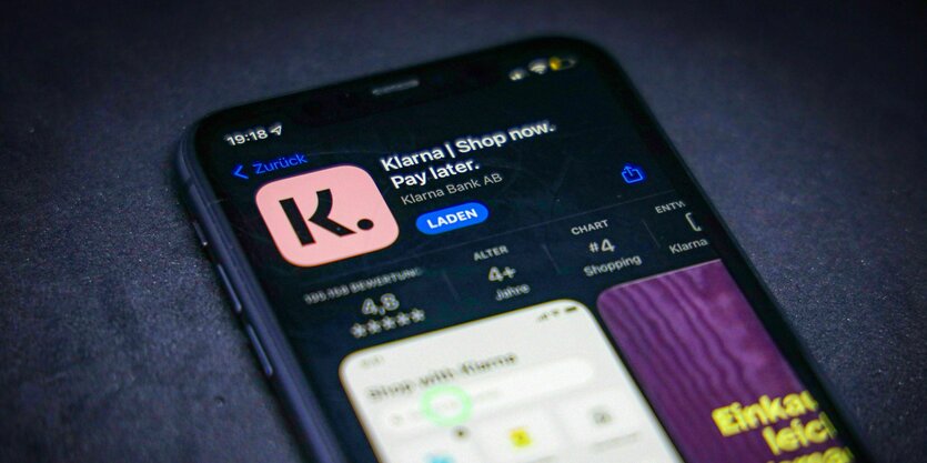 Ein Smartphone auf dem die Klarna App zu sehen ist liegt auf einem Tisch