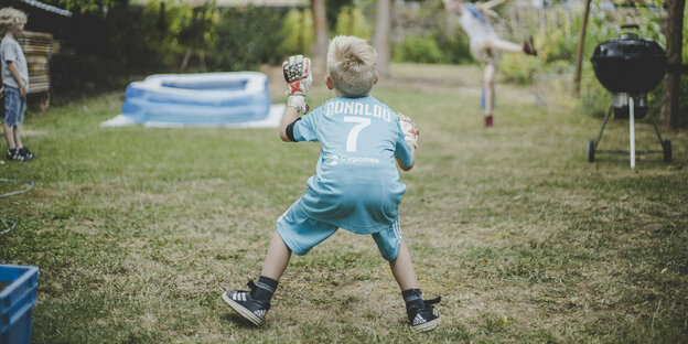 Ein Junge in einem Trikot von Ronaldo spielt im Garten Fußball