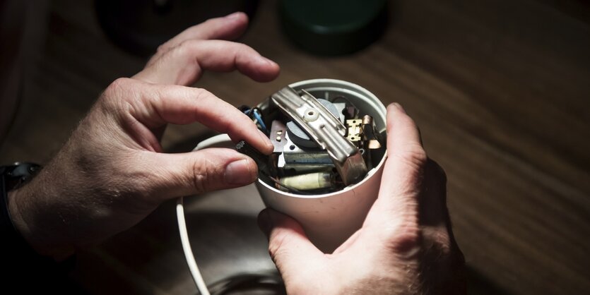 Man sieht, wie zwei Hände eine Kaffeemühle reparieren