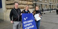 Drei Personen stehen mit blauem Plakat vor dem Hamburger Rathaus