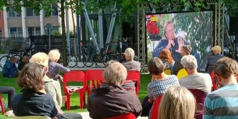 Publikum im Park vor einem Bildschirm