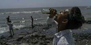 Ein Mann trinkt am Strand Cola