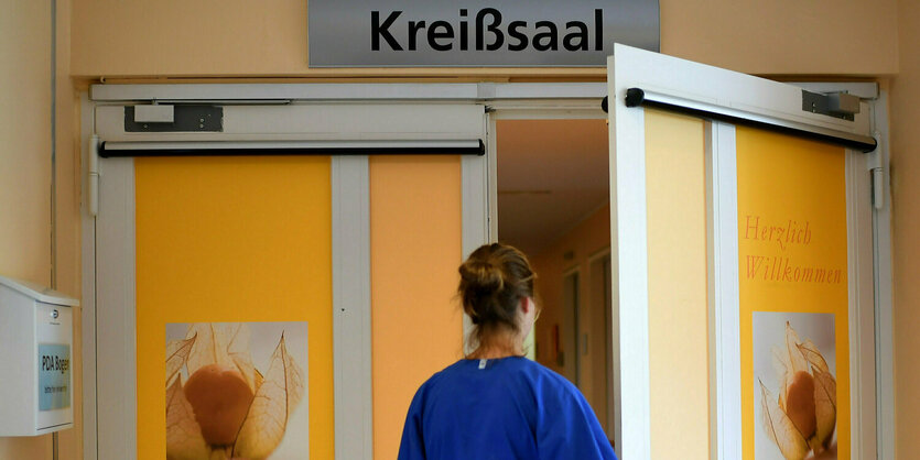 Eine Krankenschwester öffnet die Tür zum Kreißsaal