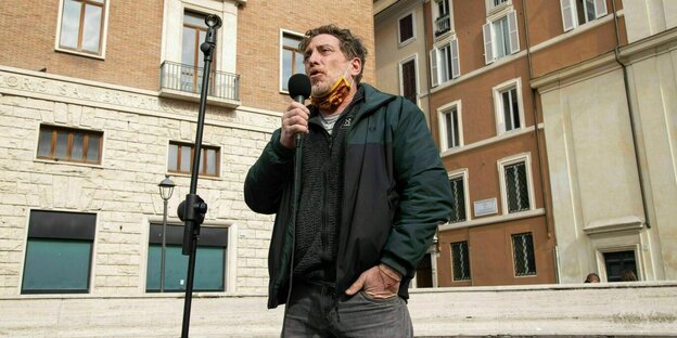 Ein Mann steht mit einem Mikrofon in der Hand auf der Straße