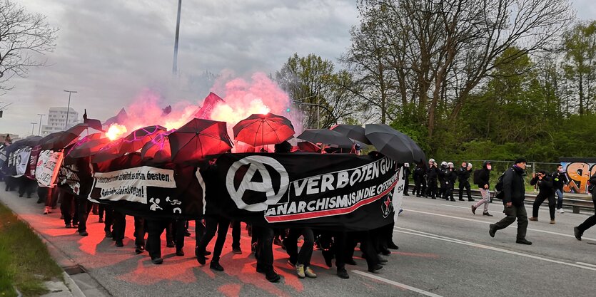 Menschen hinter Transparenten und Schirmen haben Pyrotechnik gezündet