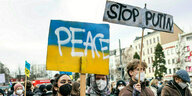 Menschen demonstrieren mit Plakaten gegen den Krieg in der Ukraine