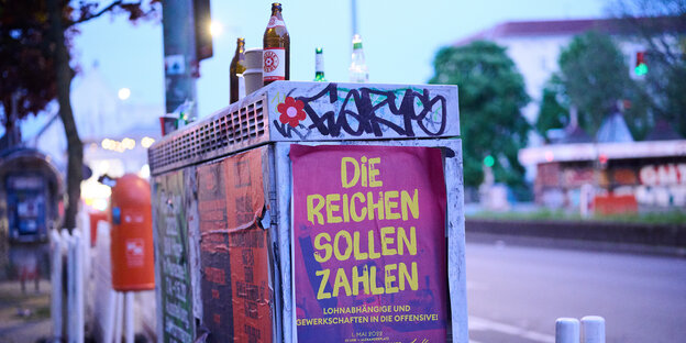„Die Reichen sollen zahlen“ steht auf dem Plakat, während Müll an der Kottbusser Straße herumliegt, wo am 1. Mai die 18-Uhr-Demonstration vorbei lief.