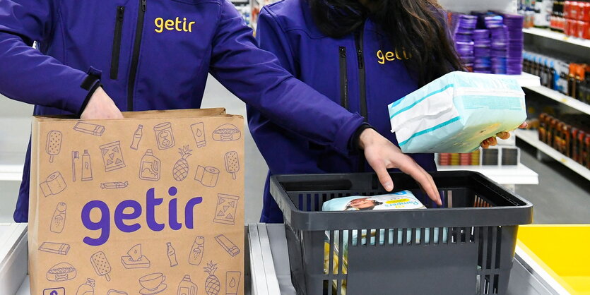 Arbeiter*innen bei Getir packen Lebensmittel in braune Packpapiertüten zur Auslieferung