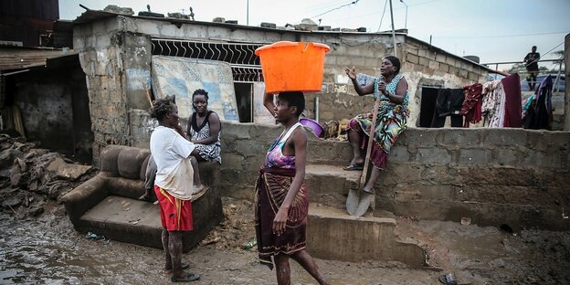 Frauen in Luanda, eine trägt eine orangefarbene Platikschüssel auf dem Kopf