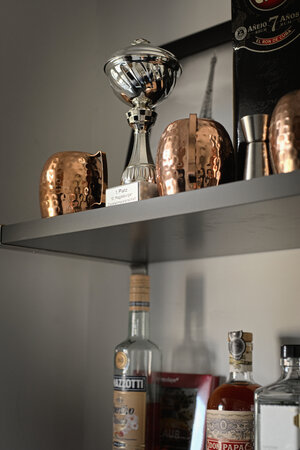 Ein Pokal, Becher und Alkoholflaschen in einem Regal Ein Pokal, Becher und Alkoholflaschen in einem Regal