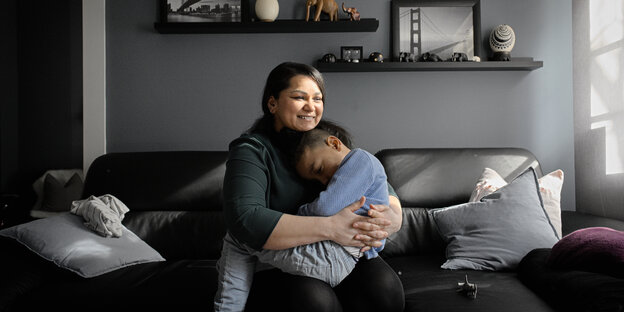 Eine Frau sitzt auf dem Sofa und umarmt ein kleines Kind