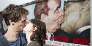 Ein Pärchen küsst sich vor dem Bruderkuss an East Side Gallery.