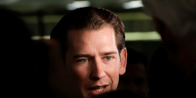 Portrait of a man with brown hair slicked back, lying partly in the shade.  It is Austria's ex-Chancellor Sebastian Kurz.