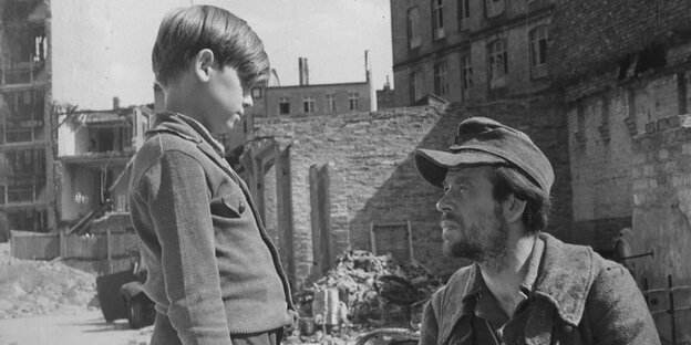 Szene aus „Irgendwo in Berlin“ (1946), von Gerhard Lamprecht: Ein Soldat knieht vor einem kleinen Jungen. Im Hintergrund Trümmer