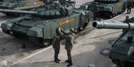 Zwei russische Soldaten proben vor Panzern die Siegesparade