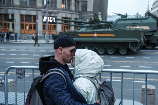 Ein junges Paar küsst sich, während ein Panzer vorbeifährt Ein junges Paar küsst sich, während ein Panzer vorbeifährt