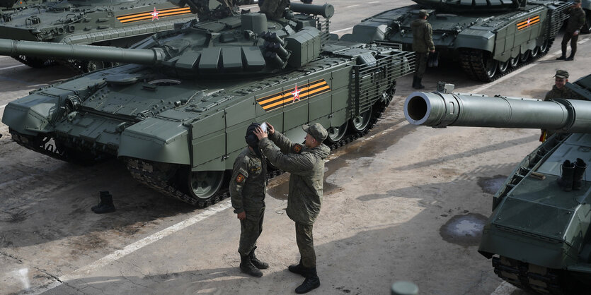 Zwei russische Soldaten proben vor Panzern die Siegesparade