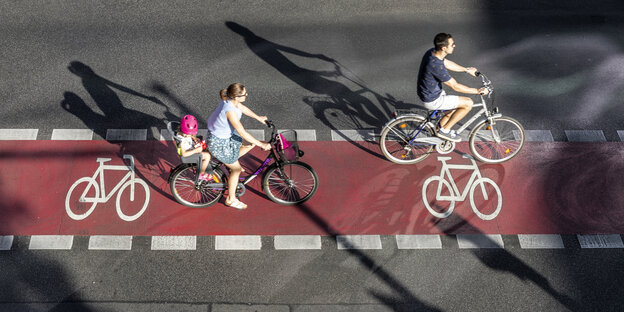 Menschen fahren mit ihren Fahrrädern auf einem rot marlierten fahrradweg