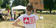 Das Bild zeigt den Rücken einer Person, die ein T-Shirt mit dem Aufdruck "Klimaneustart Berlin" trägt.