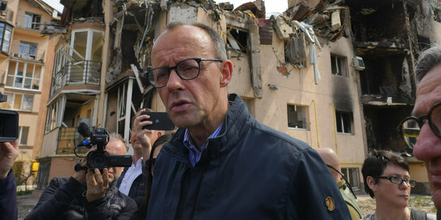 Portrait von Friedrich Merz in Irpin vor zerstörten Häusern