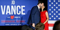 Frau in rotem Kleid küsst ihren Mann J.D. Vance auf der Bühne nach seinem Sieg