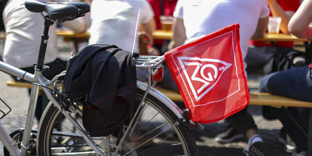Eine Fahne der IG Metall hängt an einem Fahrrad auf dem Marktplatz in Leipzig.