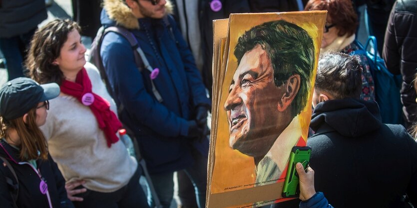 Menschen mit einem Plakat, auf dem Jean-Luc Mélenchon zu sehen ist