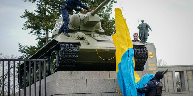 Das Foto zeigt einen zum sowjetischen Ehrenmal an der Straße des 17. Juni gehörenden Panzer, von dem eine ukrainische Flagge entfernt wird, die ihn kurzzeitig verhüllte.