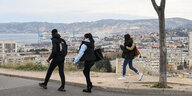 Drei Jugendliche auf einer Straße, von der aus man einen Blick auf Marseille hat