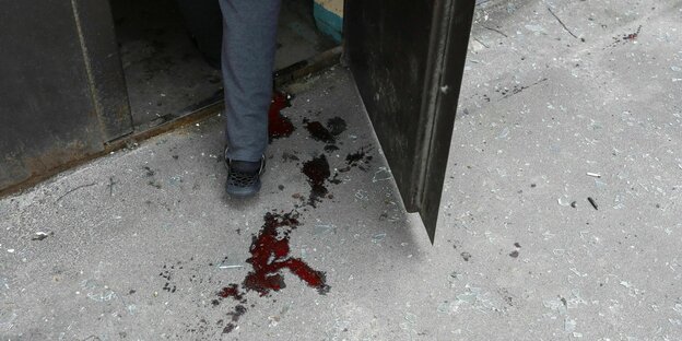 Füße eines Mannes machen Blutspuren auf einem Betonboden