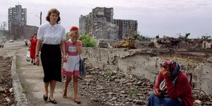 Eine Frau mit einem kleinen Mädchen an der Hand läuft durch eine Trümmerlandschaft