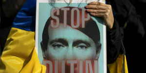 Ein Plakat mit dem gesicht von Putin und der Aufschrift "Stop Putin"