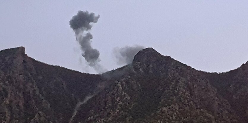 Rauch steigt über Berggipfeln auf