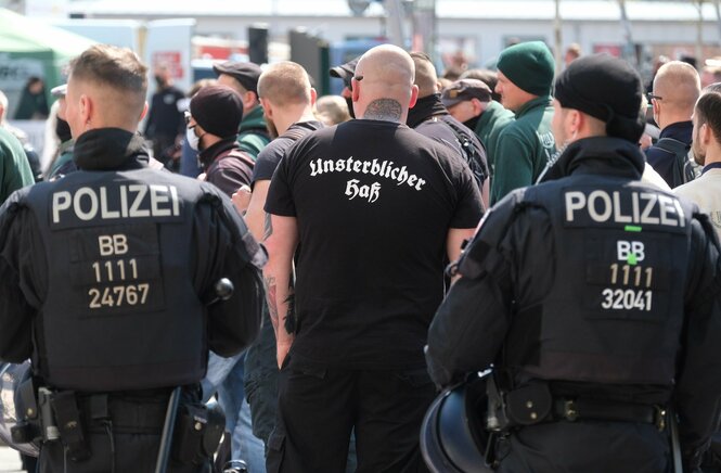 Polizisten stehen hinter demonstrierenden Neonazis