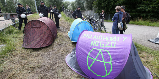 Polizisten stehen hinter zwei Zelten