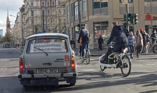 ein Trabi mit einem Schild für ein bedingungsloses grundeinkommen