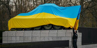 Ein in eine ukrainische Flagge gehüllter sowjetischer Panzer steht auf einem Sockel