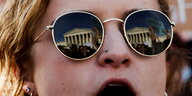Eine Demonstration steht vor dem Obersten Gerichtshof der USA - in ihrer Sonnebrille spiegelt sich das Gebäude