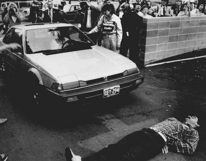 Ein Mann liegt bei Protesten vor einem Auto auf der Straße