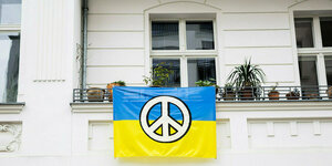 Eine ukrainische Fahne mit Peace-Zeichen hängt an einer Balkonbrüstung