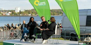 Drei Politiker und Politikerinnen der Grünen sitzen auf einem Podium
