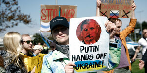 Ein Mann hält ein Plakat gegen Putin hoch