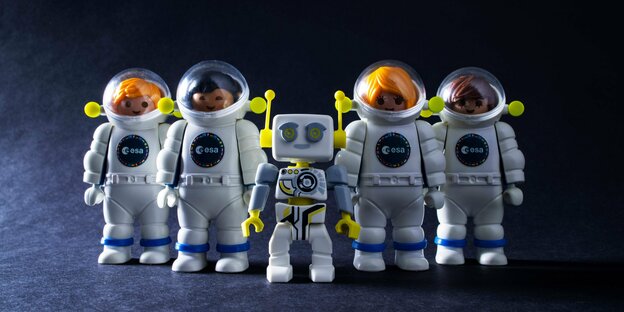 Fünf Legofiguren - vier Astronauten und ein Roboter - stehen in einer Reihe