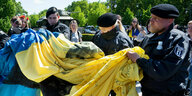 Polizisten wickeln eine große Ukrainische Fahne bei einer Gedenkveranstaltung vor dem Sowjetischen Ehrenmal im Tiergarten zusammen