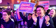 CDU-Anhänger in Kiel reagieren enthusiastisch auf erste Hochrechnungen. Auf einem Schild steht Daniel Günther