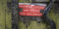 Ein Schild mit der Aufschrift "Geeinte deutsche Völker und Stämme – Amt Zehlendorf" hängt an einem Briefkasten vor einem Berliner Wohnhaus.