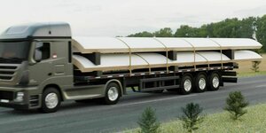 Lastwagen der mit Teilen von zwei Holz-Rotorblättern beladen ist