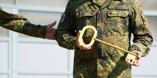 Ein überdimensionierter goldener Schlüssel wird von einem Mann in Uniform gehalten